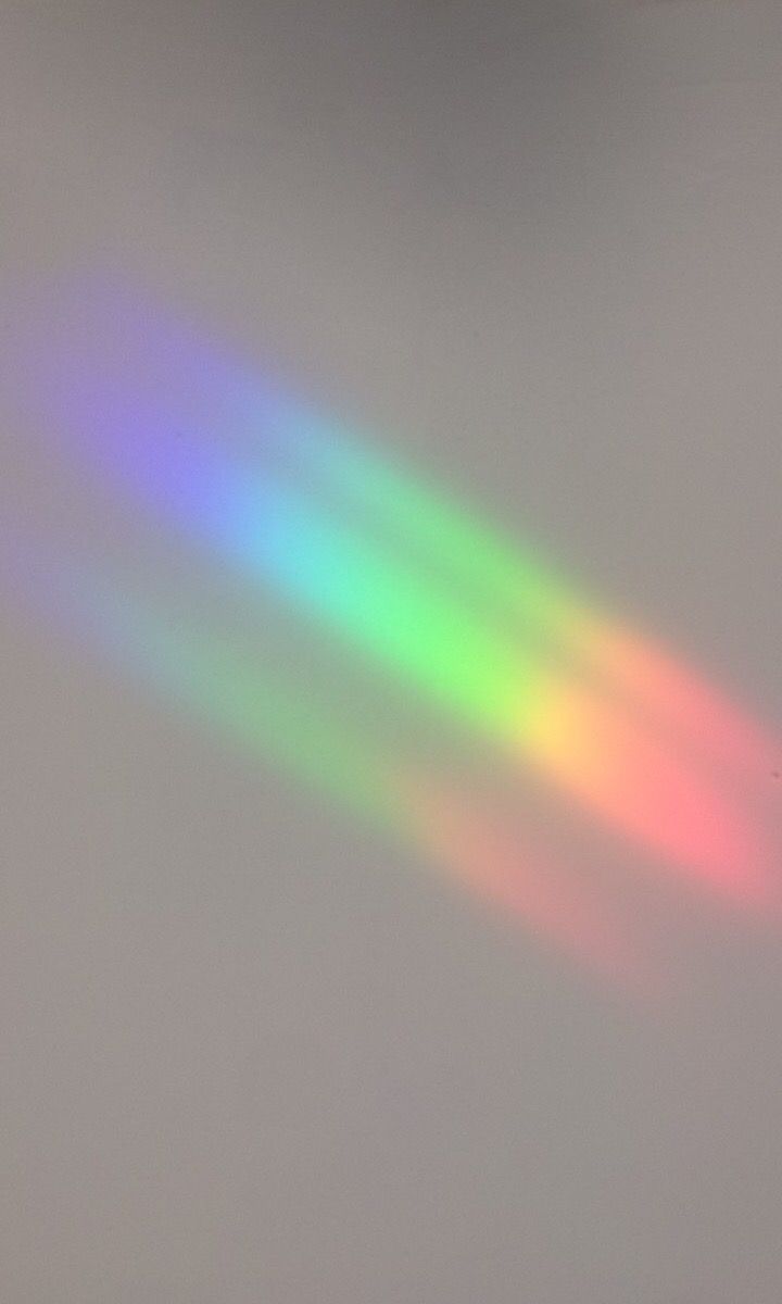 an airplane flying in the sky with rainbow colored light coming from it's tail