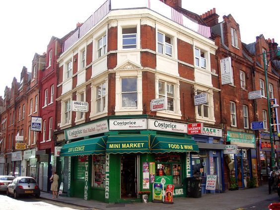 a street corner with stores and cars parked on the side walk in front of it