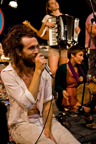 a man with long hair and beard sitting in front of an instrument while singing into a microphone