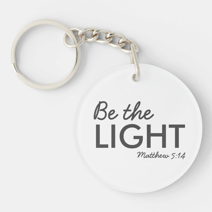 a white keychain with the words be the light written in black on it