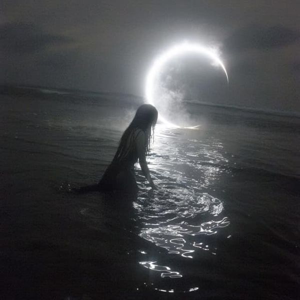 a woman standing in the water with her back to the camera