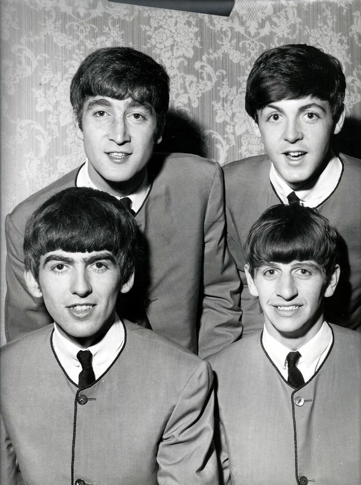 the beatles are posing for a photo in their suits and ties, with one man's head tilted to the side