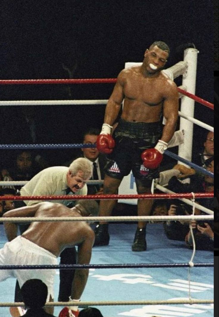 two men standing next to each other in a boxing ring with referee looking at them