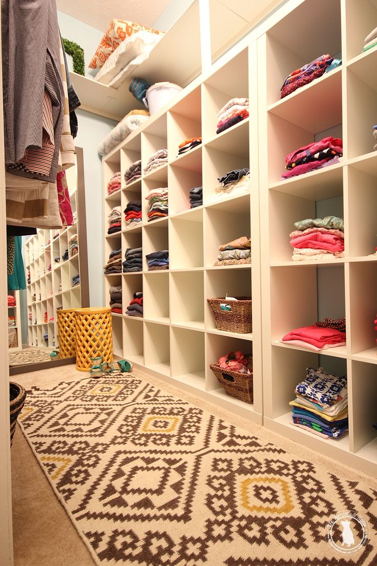 the closet is filled with lots of clothes and baskets on shelving units, including an area rug