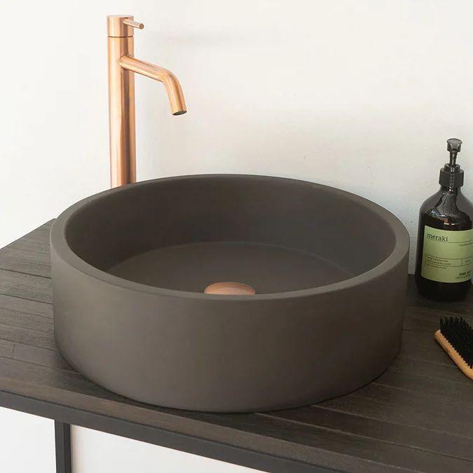 a bathroom sink sitting on top of a wooden counter next to a brush and soap dispenser