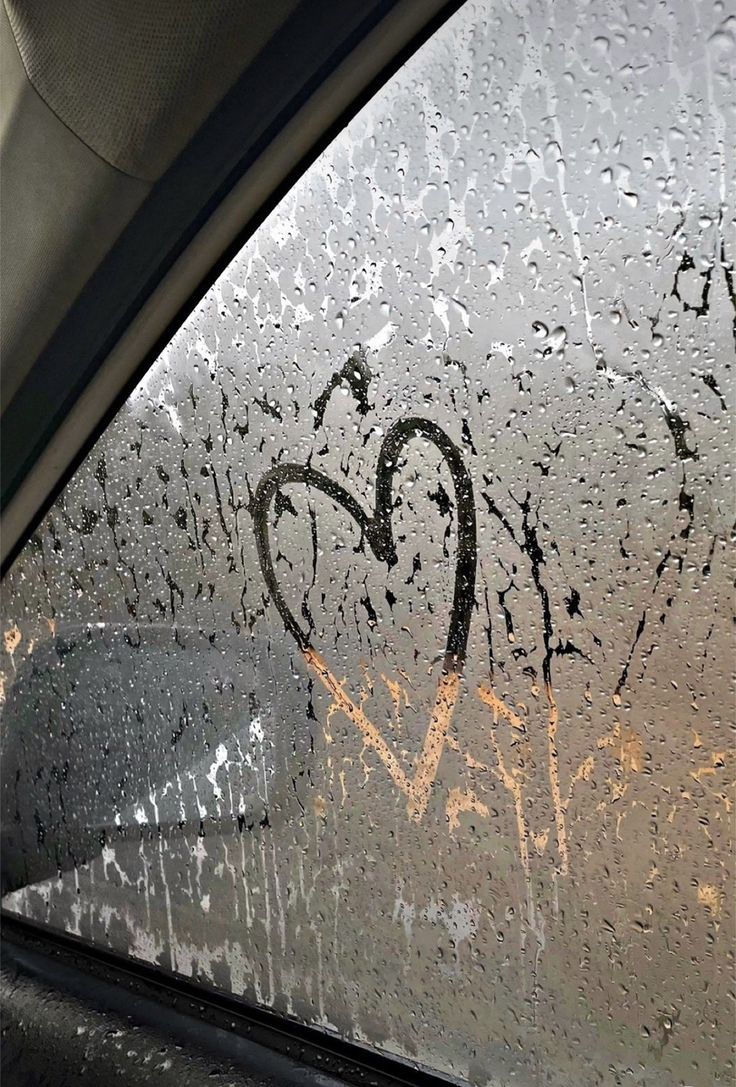 a car window covered in rain and graffiti