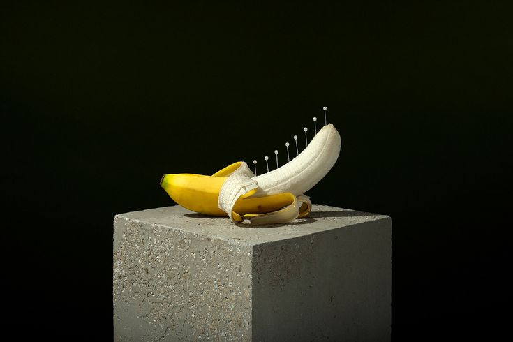 a banana sitting on top of a cement block with pins in it's middle