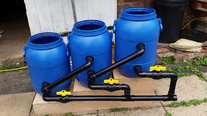 three blue water tanks with yellow handles and hoses connected to them on a pallet