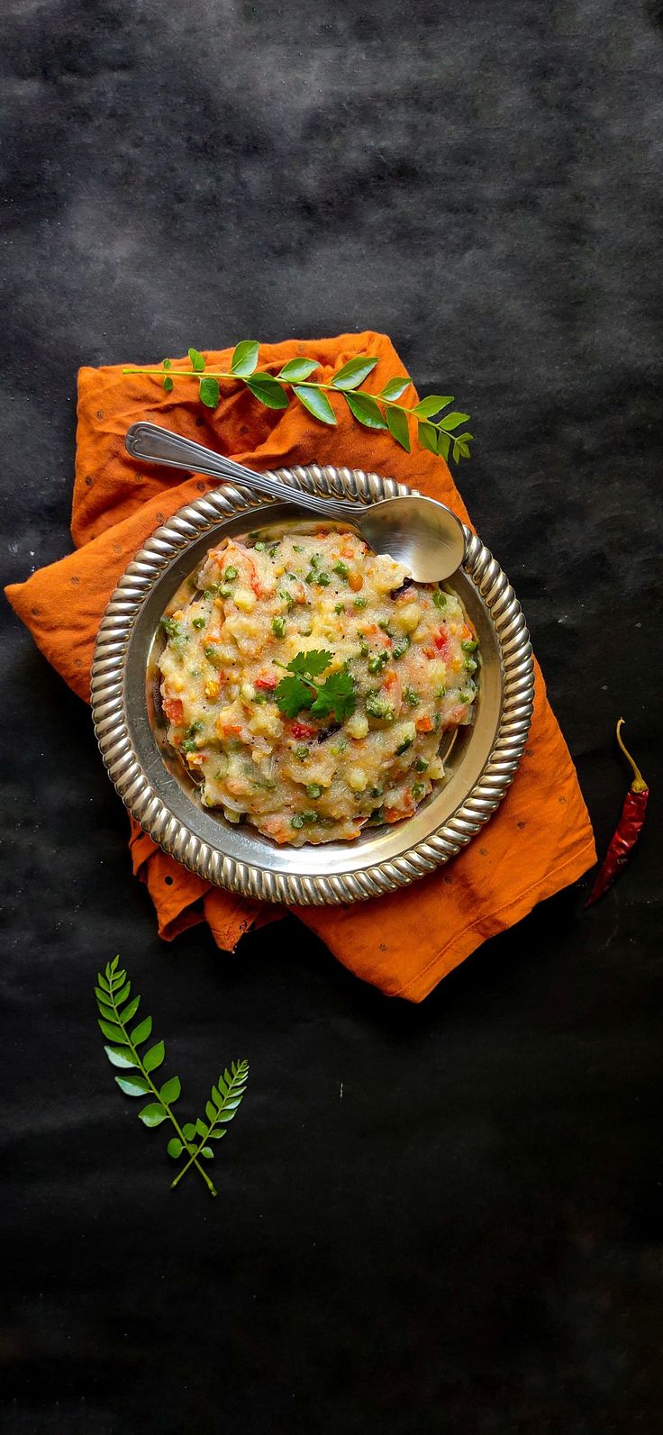 a bowl of food on top of an orange napkin next to a fork and spoon