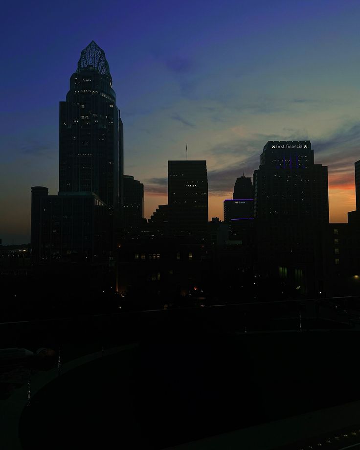 the city skyline is lit up at night, with skyscrapers in the foreground