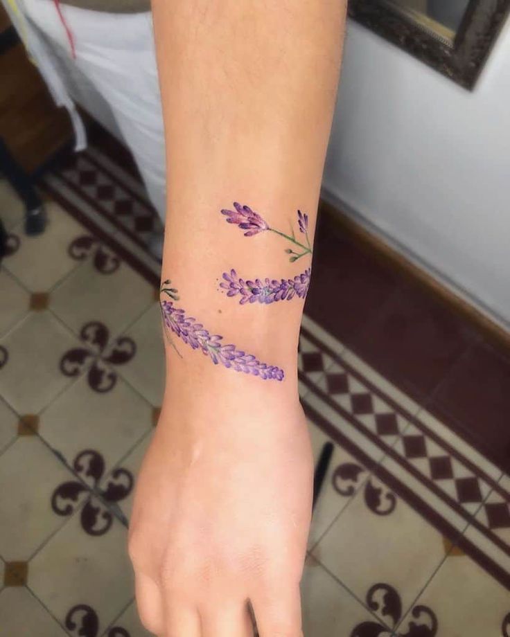 a woman's hand with a purple flower tattoo on her left arm and wrist