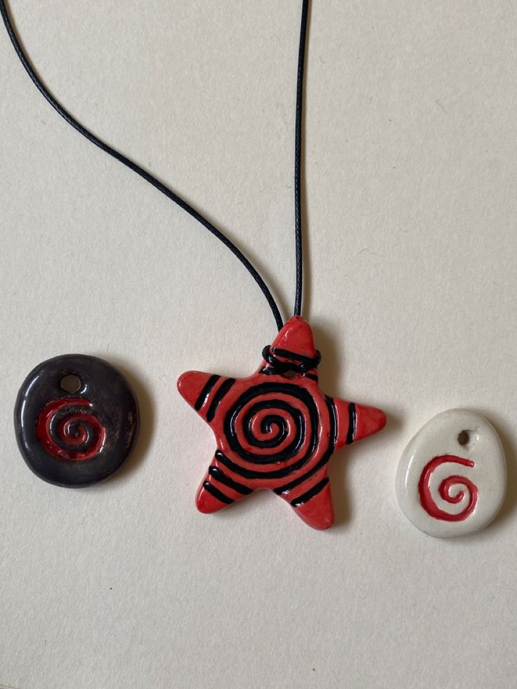 two necklaces with different designs on them sitting next to each other and one has a button