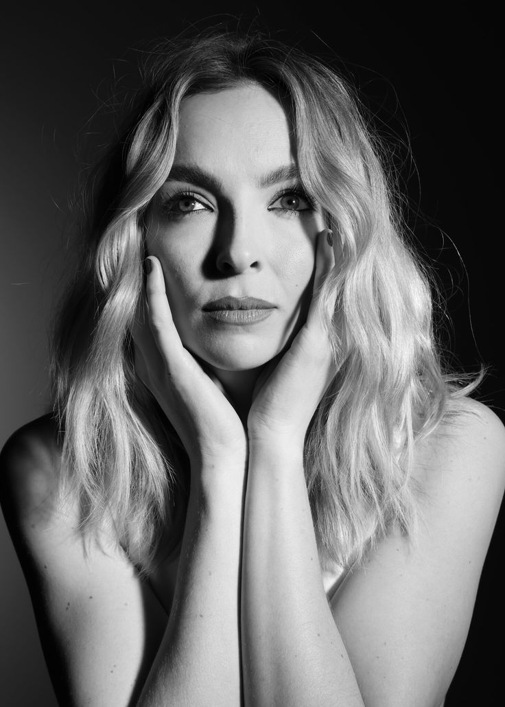 a black and white photo of a woman with her hands on her face looking at the camera