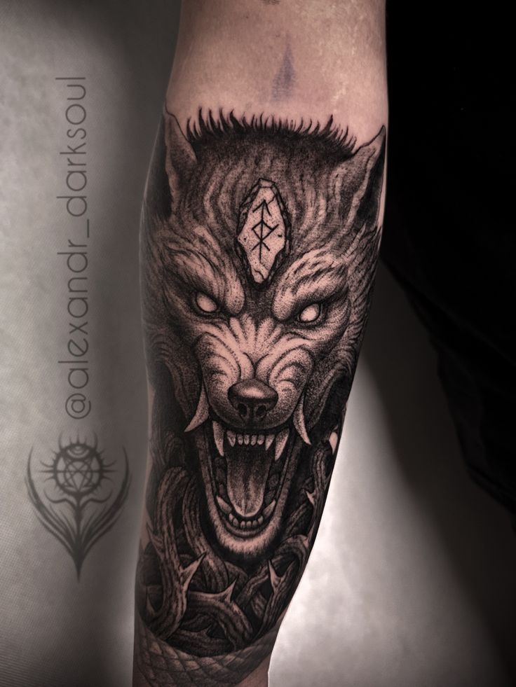 a man's arm with a black and grey tattoo design on it, featuring an angry wolf