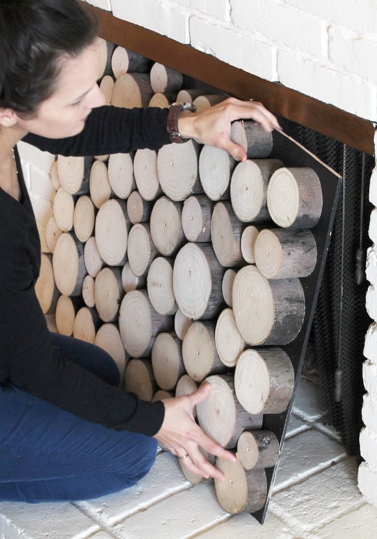 a woman sitting on the floor next to a pile of logs with her hands on it