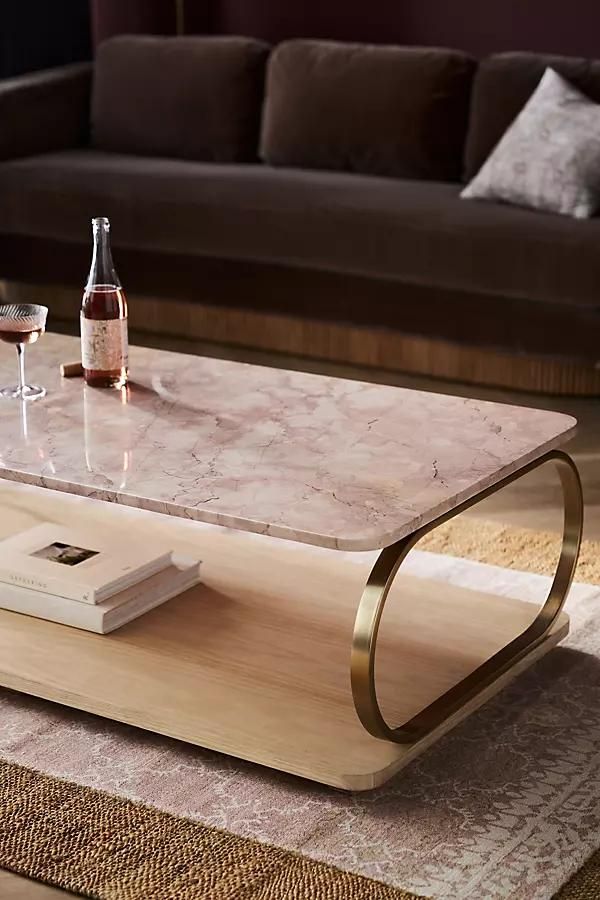 a marble coffee table with two wine glasses and a book on it in front of a couch