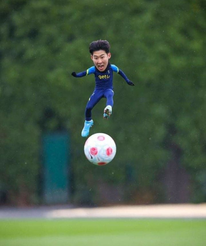 a soccer player is jumping in the air to catch a ball with his legs and head