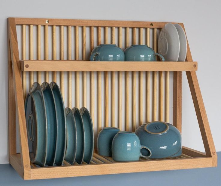 a wooden shelf filled with plates and cups on top of each other next to a wall