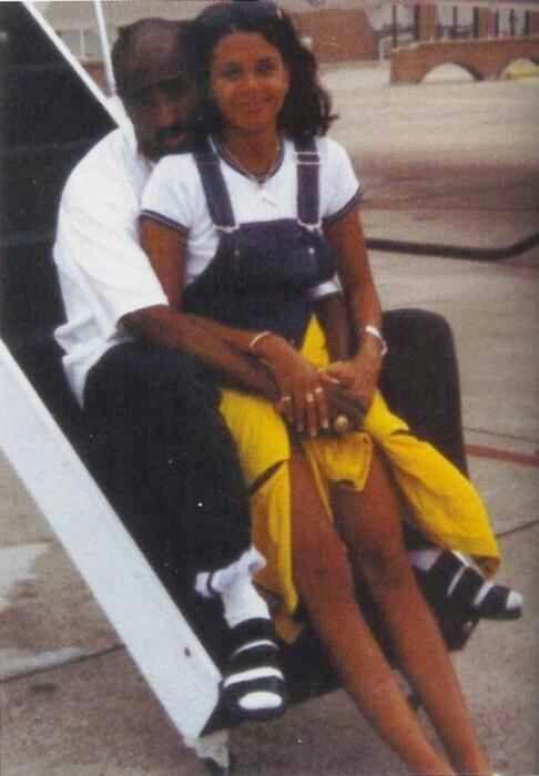 a man and woman sitting on top of an airport luggage cart next to each other