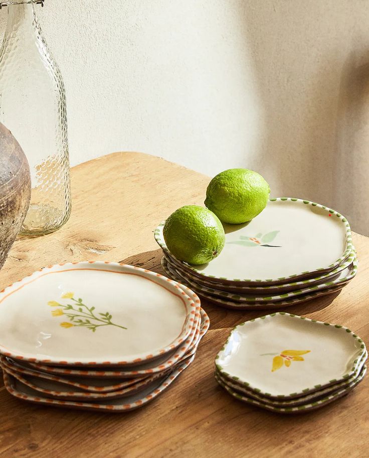 three limes sitting on top of each other on a wooden table next to plates