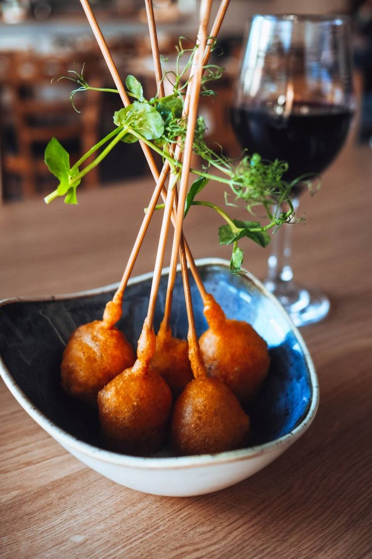 some food is sitting in a bowl on a table next to a glass of wine