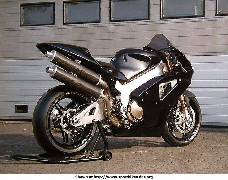 a black motorcycle parked in front of a garage door next to a metal object on the ground