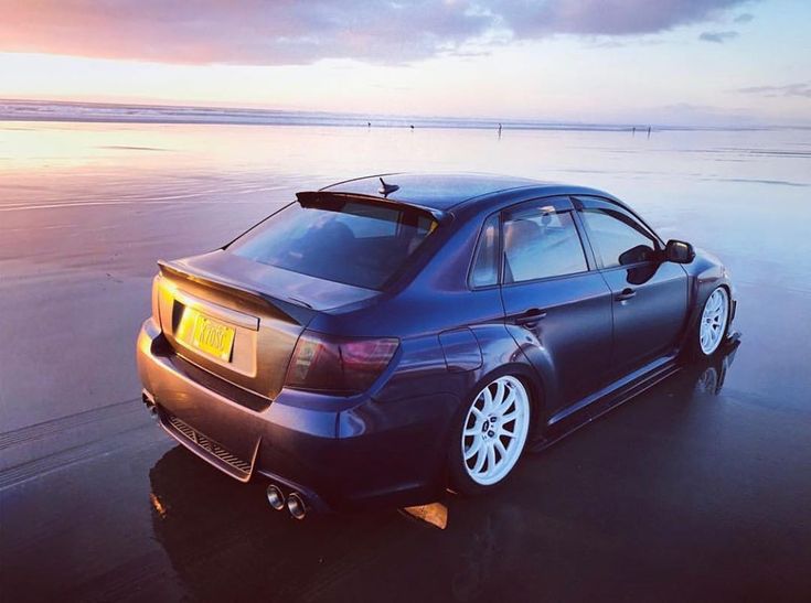 a car parked on the beach at sunset