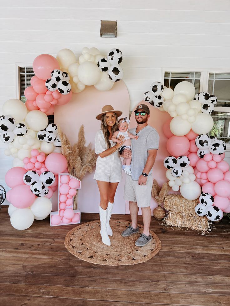 a man and woman standing next to each other in front of balloons