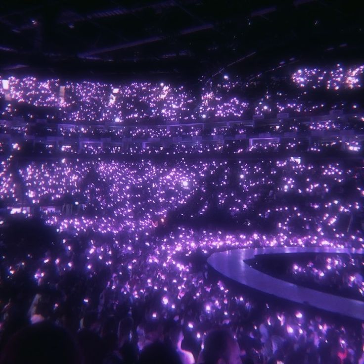 a large group of people standing in front of a stage with lots of lights on it