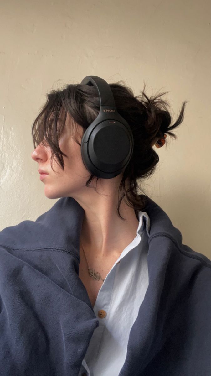 a woman wearing headphones sitting in front of a wall