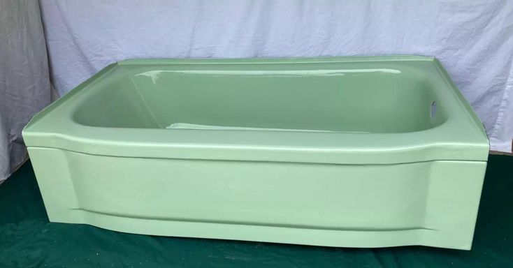 a green bathtub sitting on top of a green floor next to a white curtain