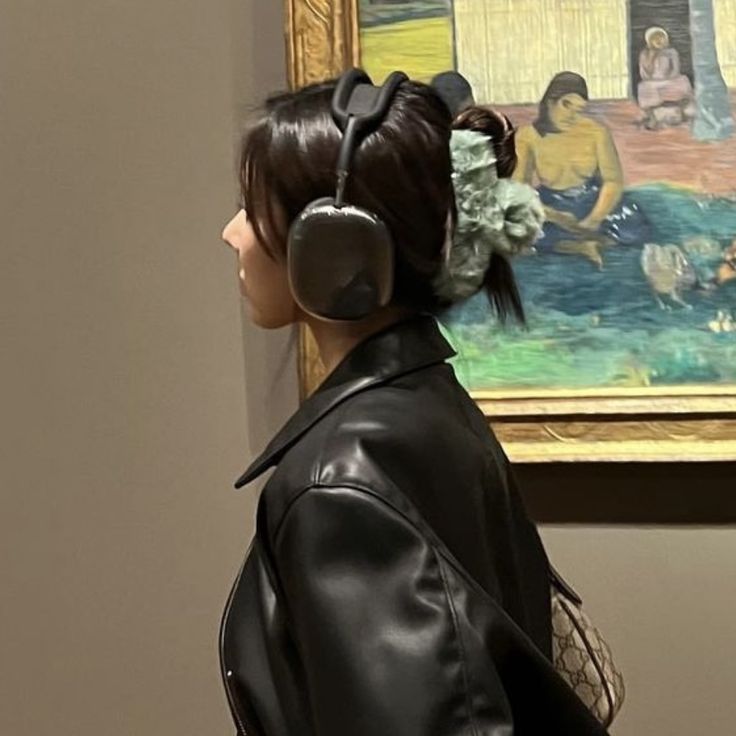 a woman with headphones standing in front of a painting