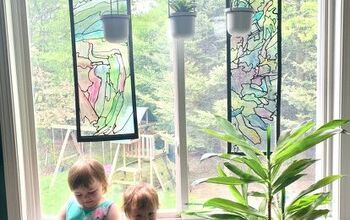 two young children sitting on a window sill in front of a potted plant