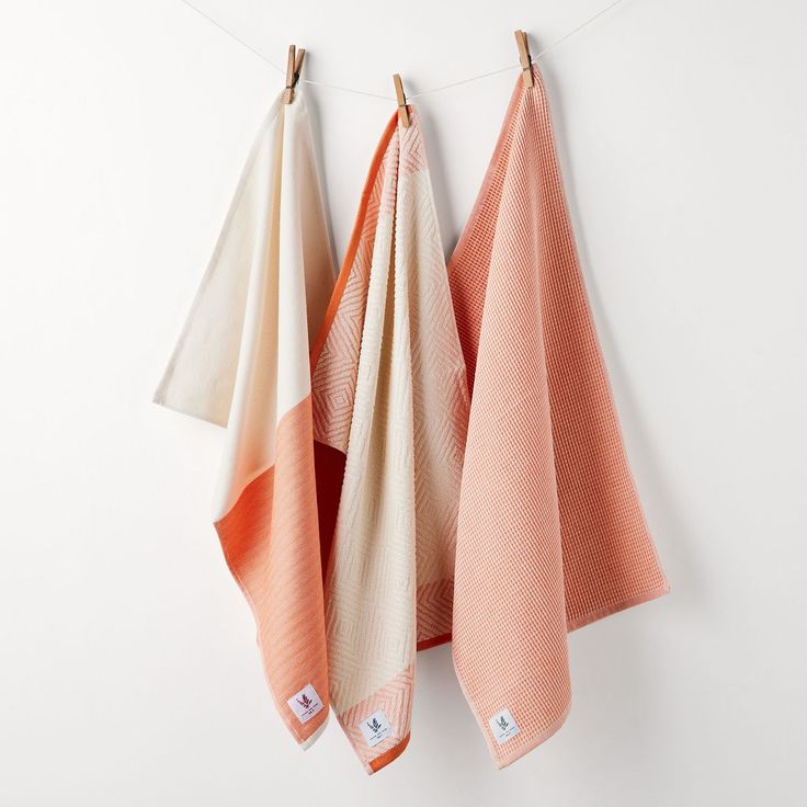 three orange and white towels hanging on a clothes line