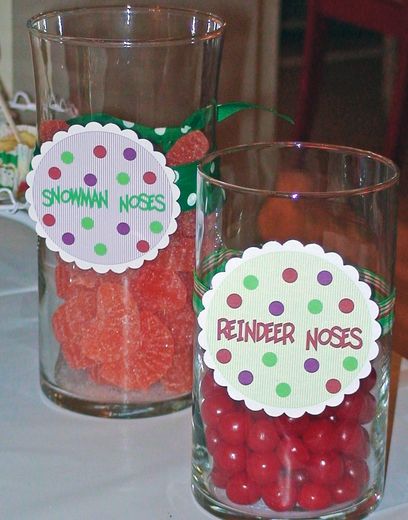 two glasses filled with candy sitting on top of a white table cloth covered tablecloth