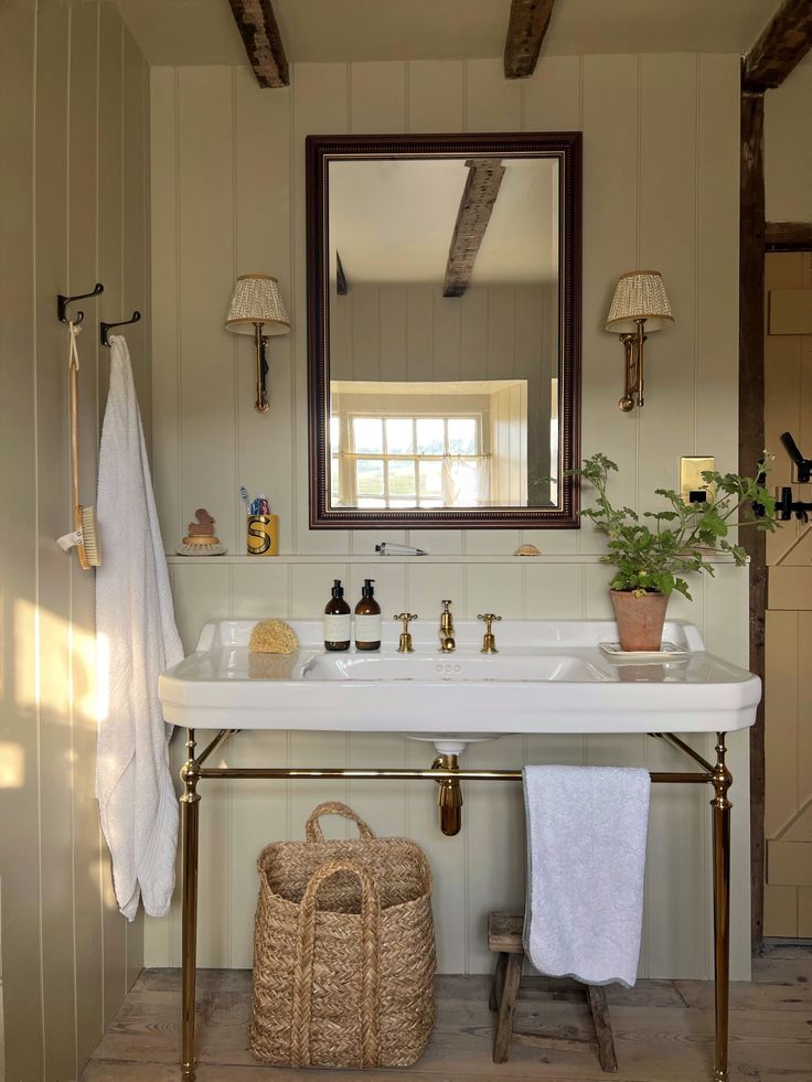 a white sink sitting under a bathroom mirror next to a wooden shelf filled with towels