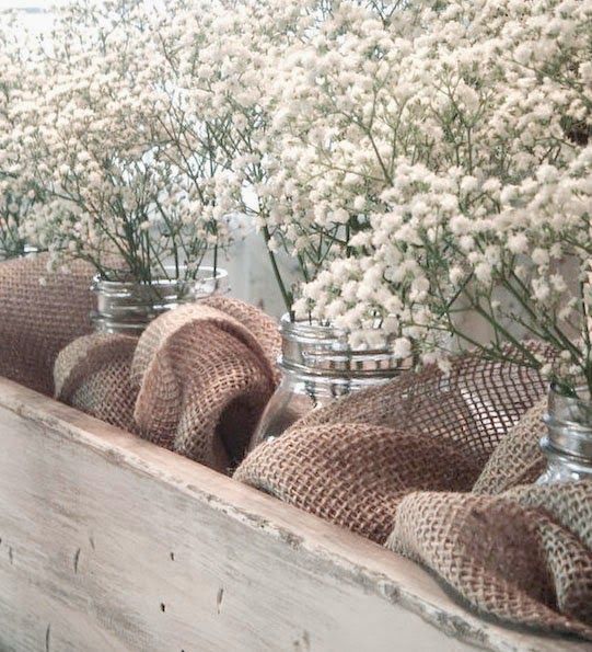 several mason jars filled with baby's breath sitting on top of a wooden shelf