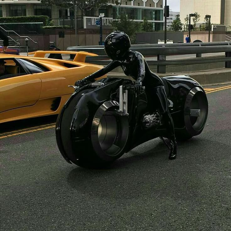 black and white photograph of a person riding a motorcycle on the road with cars in the background