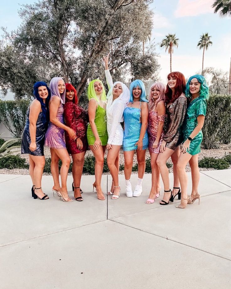 a group of women standing next to each other in front of a tree and bushes