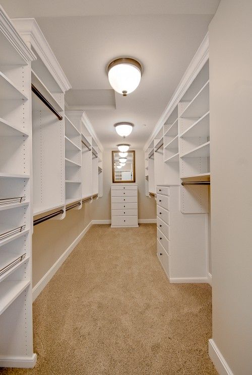 a large walk in closet filled with lots of white shelves