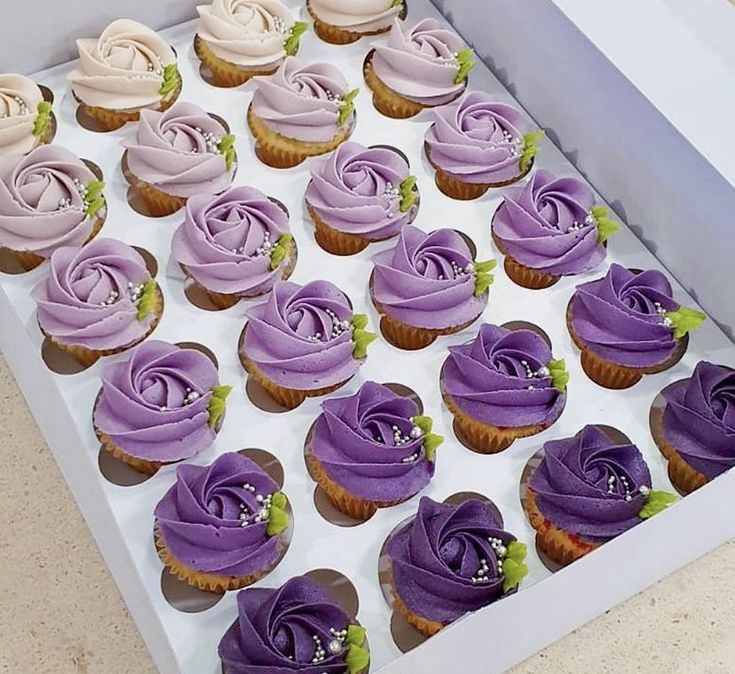 a box filled with lots of purple cupcakes