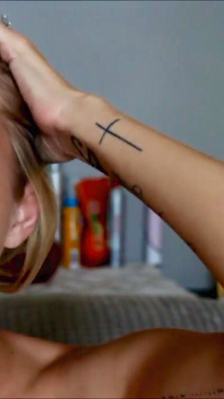 a woman with a cross tattoo on her left arm and right arm behind her head