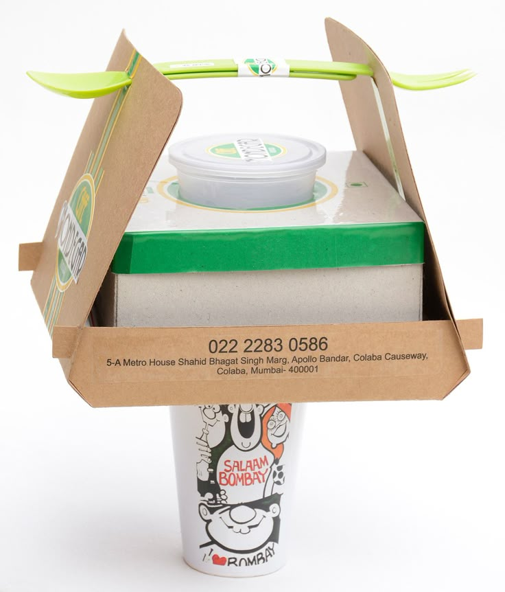 an open cardboard box containing a coffee cup and two green straws on the top