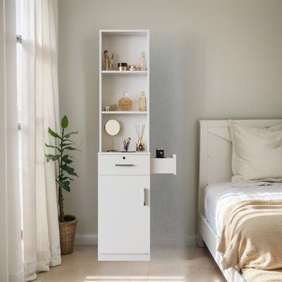 a bedroom with a bed and a white cabinet in the corner next to a window