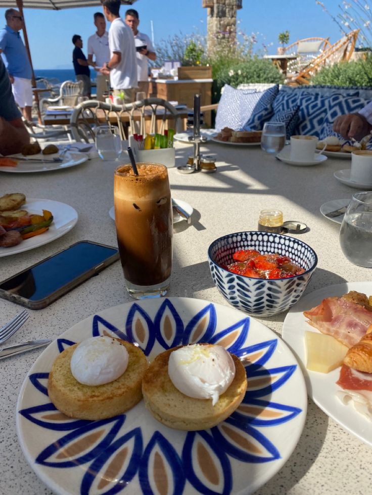 an outdoor table with plates of food and drinks