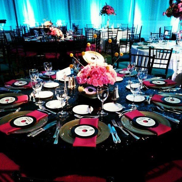 the table is set with plates, silverware and pink flowers in centerpieces