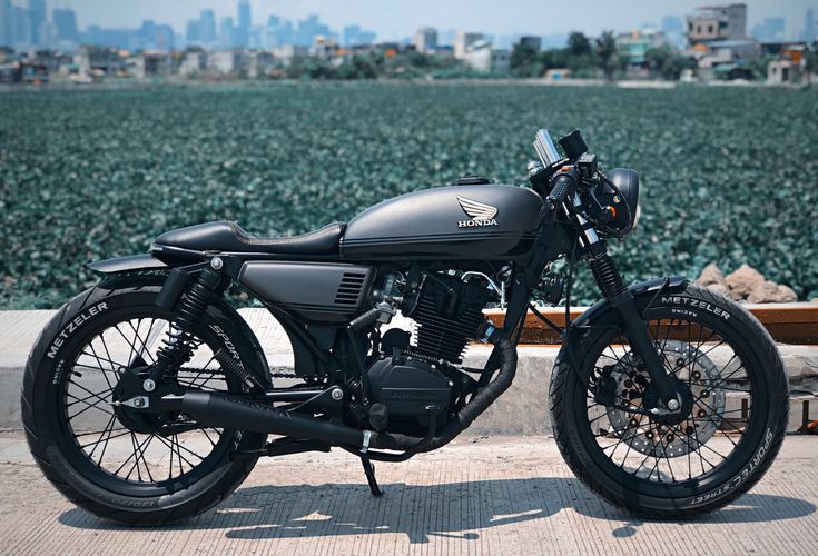 a black motorcycle parked on the side of a road next to a body of water