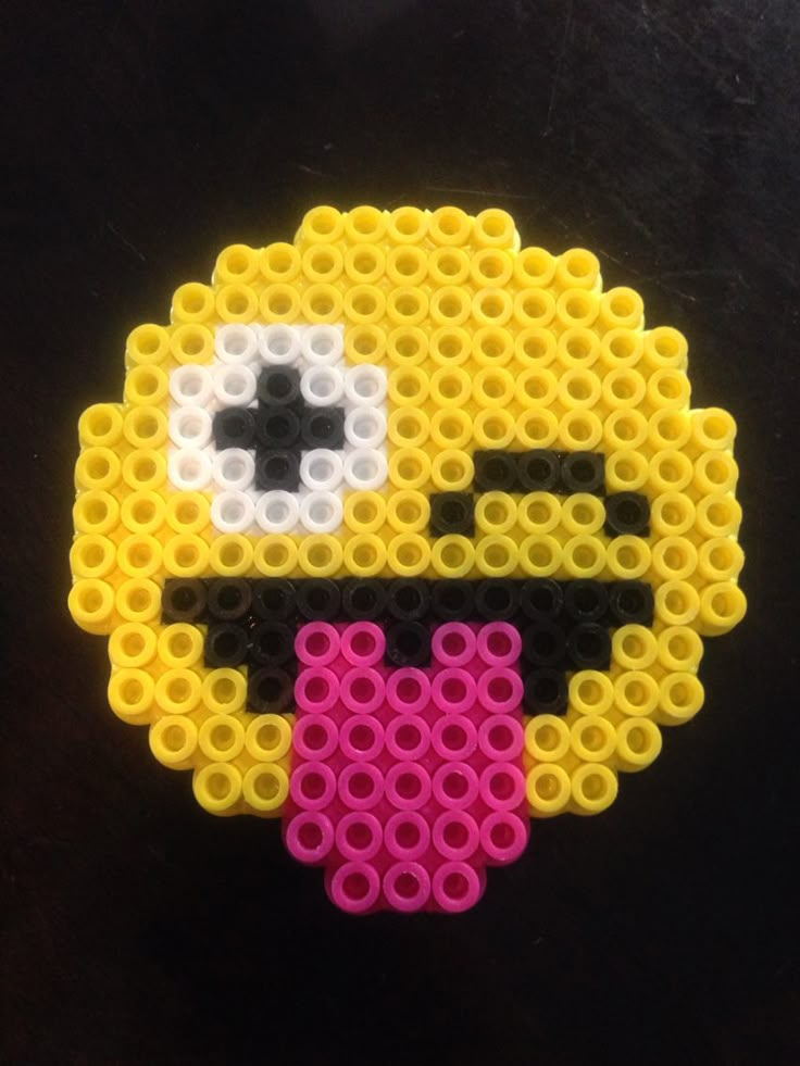 an image of a beaded skull on a black surface with yellow and pink beads