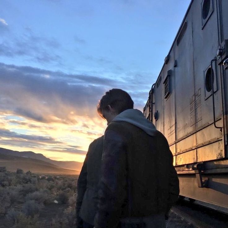 a man standing in front of a train at sunset