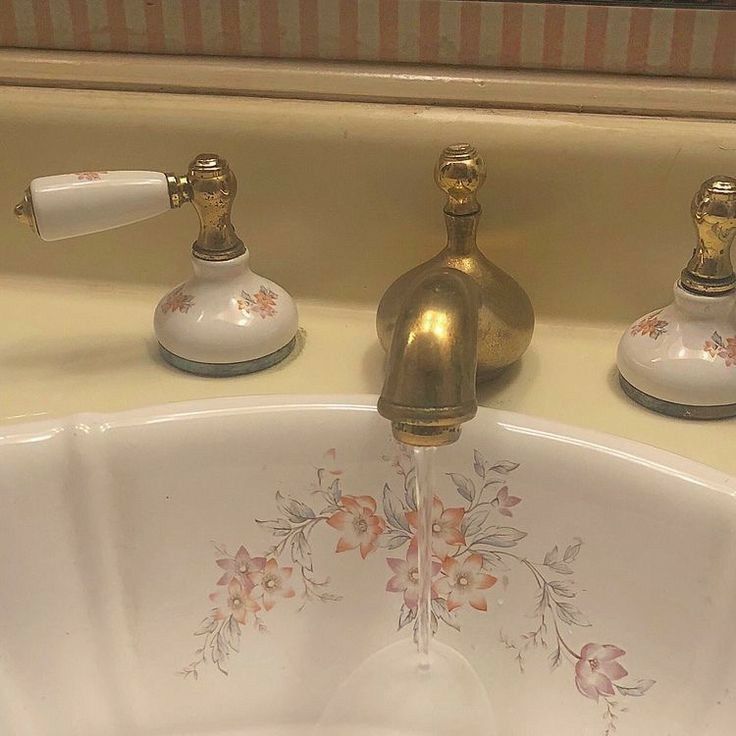 three faucets with flowers painted on them in a bathroom sink